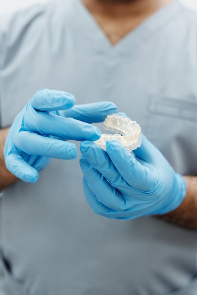 Person in Gray Scrub Suit Wearing Blue Latex Gloves